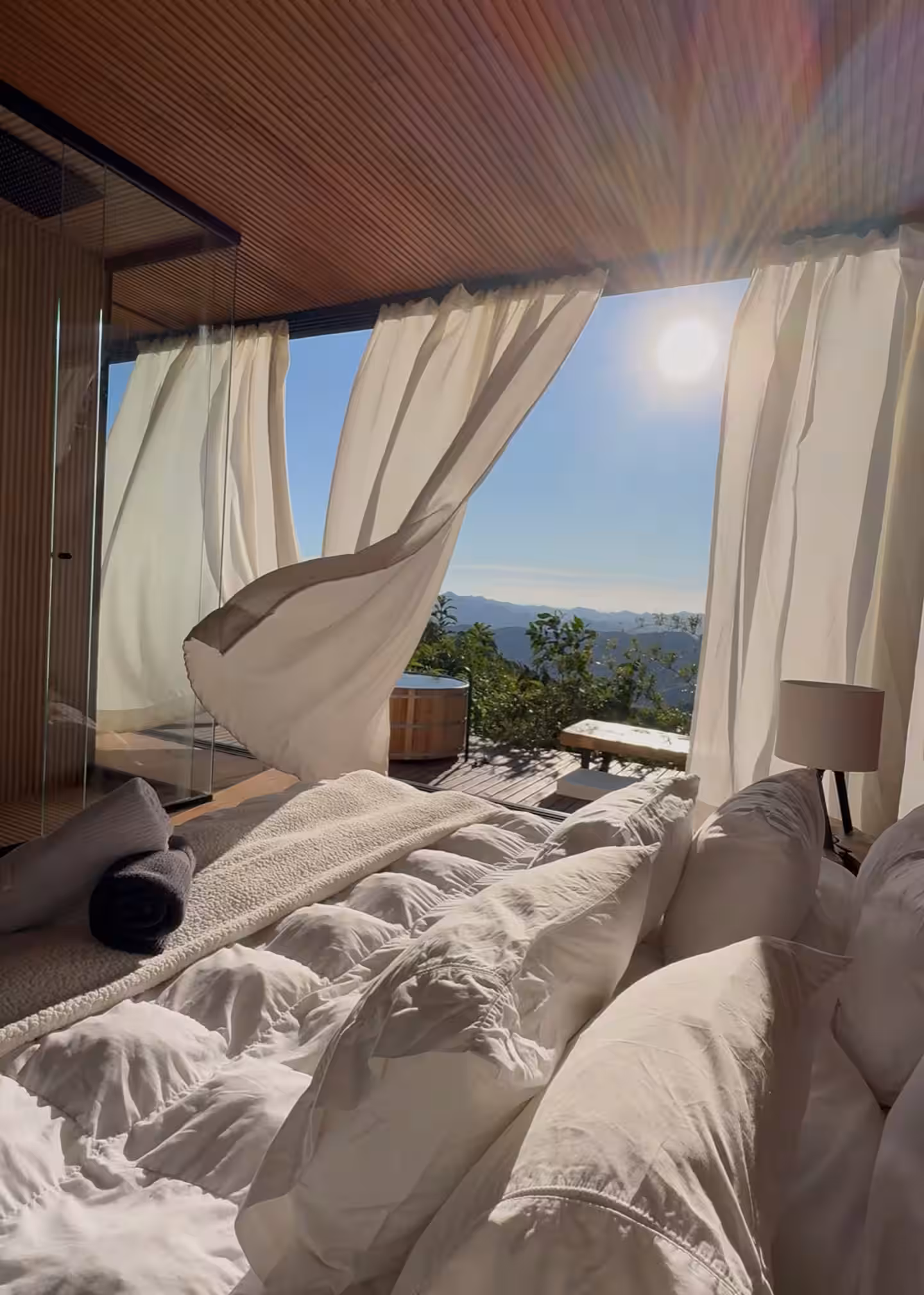 Cama king aberta para o deck e a vista da serra